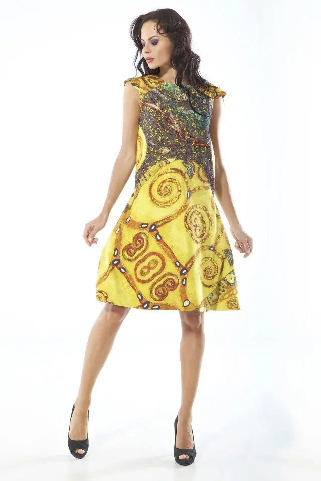 Model wearing a short dress in golden hues inspired by Gustav Klimt’s The Lady in Gold, with Batman graphic lace panels at the bust.